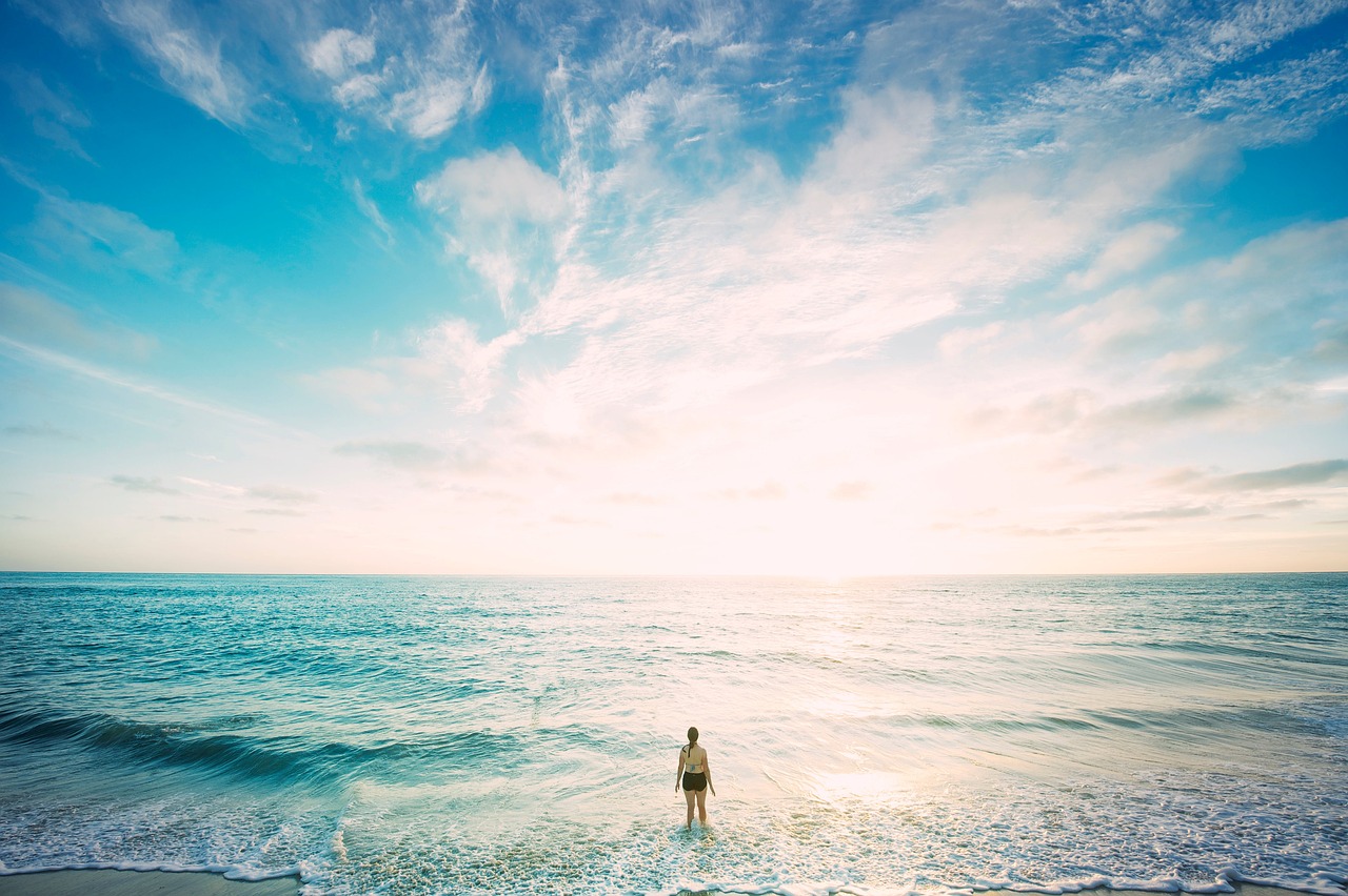 人生の道しるべになる光がさした海の前に佇む女性