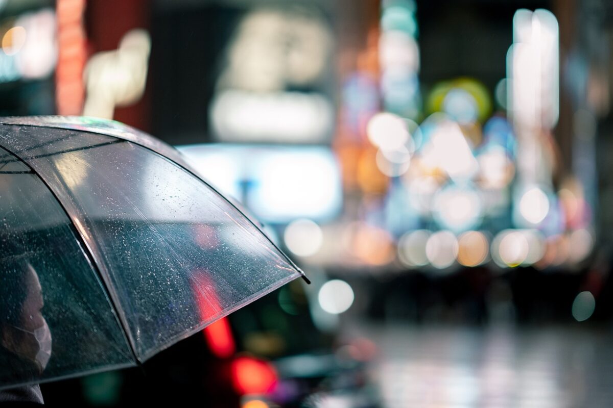 雨の中、傘を差してうまくいかないなと落ち込む女性